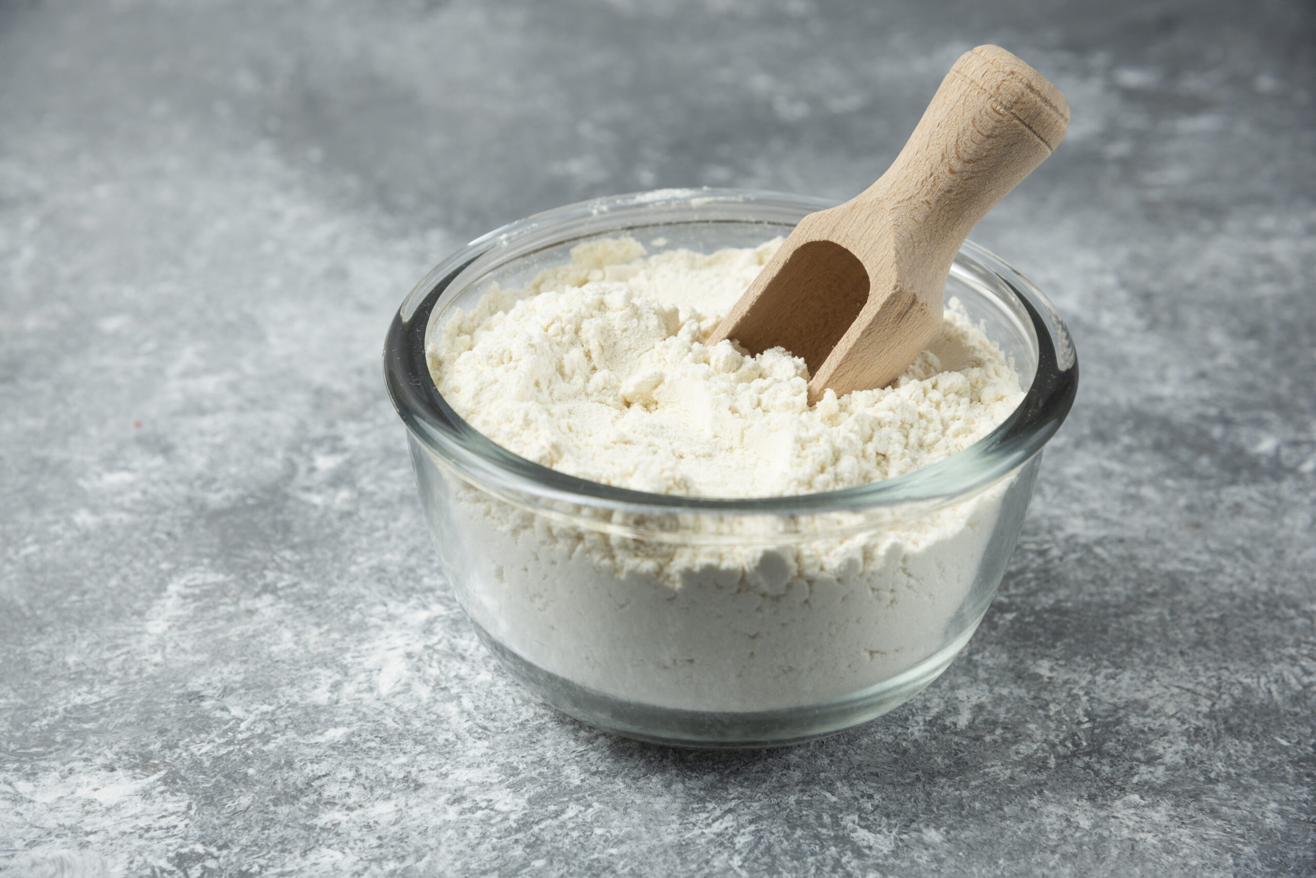 Glass bowl of flour on marble background